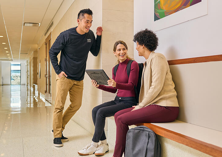 A group of students sitting on a bench, engaged in conversation 