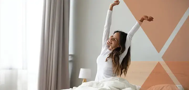 Person sitting in bed stretching arms after sleep 