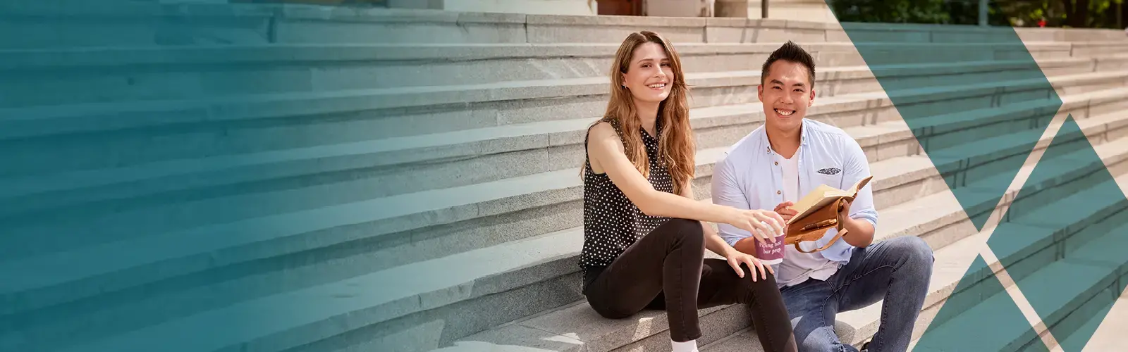 Two students sitting on steps, holding a coffee and notebook