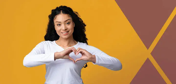 Beautiful Young Woman Making Heart Gesture With Hands Near Chest